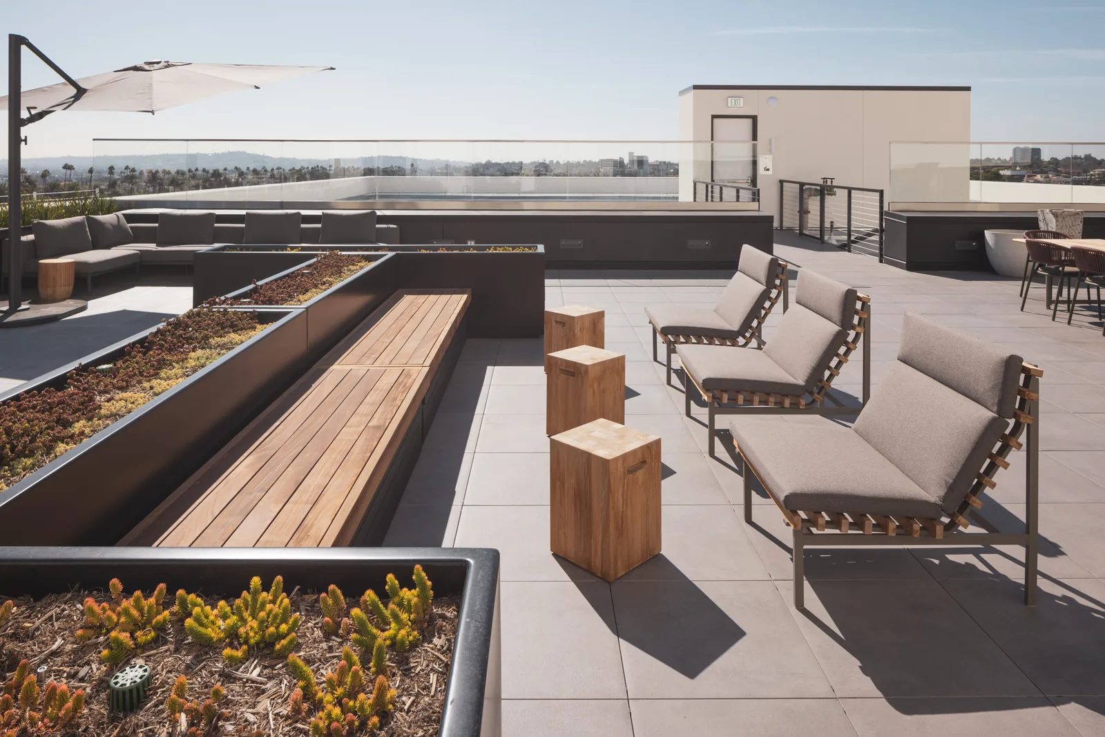 Rooftop sofas and lounge chairs with succulent planters and a parasol